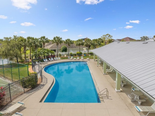 community pool with a patio area and fence