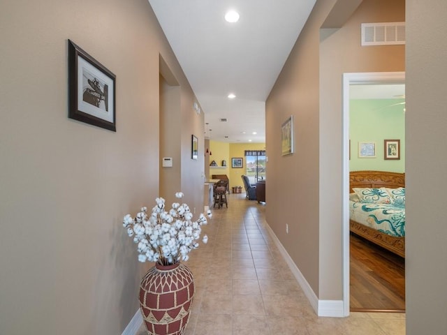 corridor featuring light tile patterned floors, baseboards, visible vents, and recessed lighting