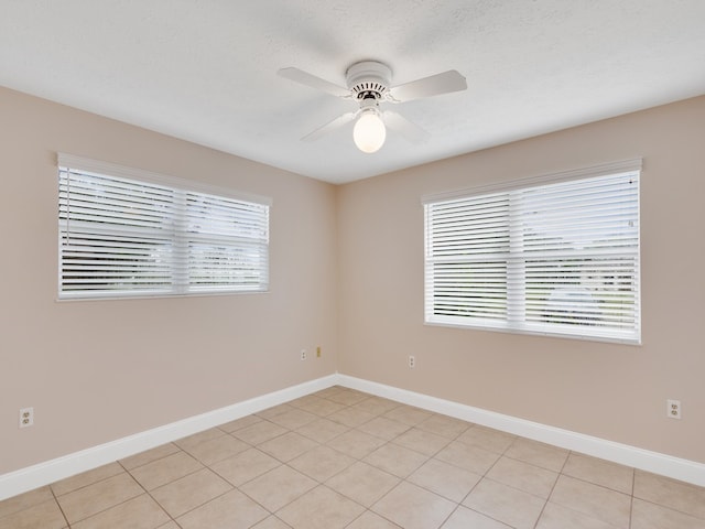 empty room with light tile patterned flooring, ceiling fan, and a textured ceiling