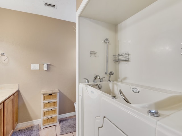 bathroom with a bathtub, vanity, and tile patterned floors