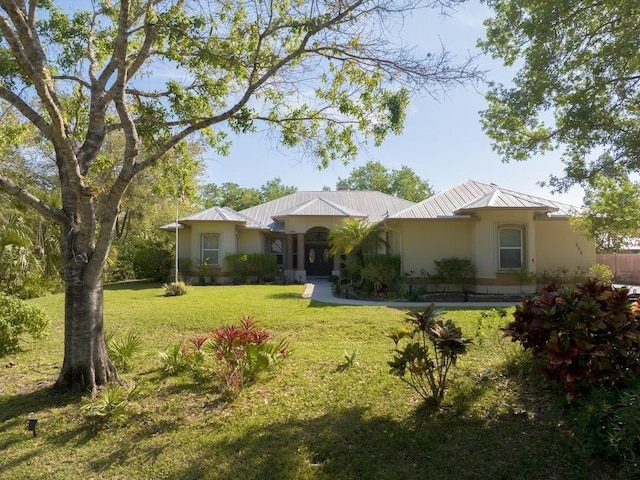 ranch-style house featuring stucco siding, metal roof, and a front lawn