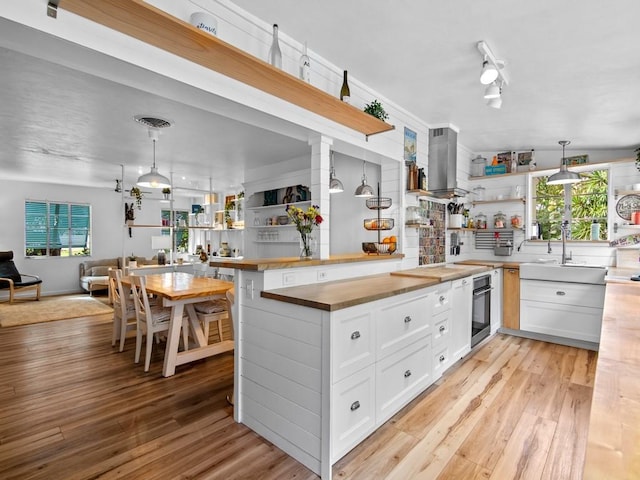 kitchen featuring butcher block counters, open floor plan, oven, light wood-style floors, and open shelves