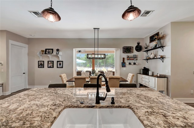 kitchen with sink, decorative light fixtures, and light stone countertops