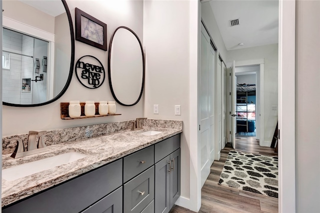 bathroom with walk in shower, vanity, and hardwood / wood-style floors