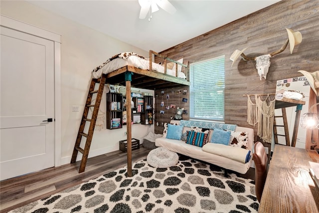 living room with wooden walls, hardwood / wood-style floors, and ceiling fan