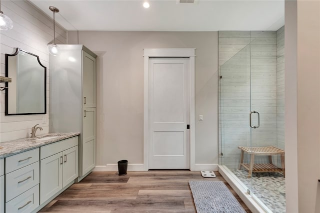 bathroom with wood-type flooring, vanity, wooden walls, and an enclosed shower