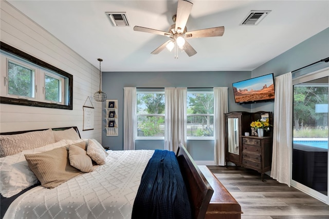 bedroom with dark hardwood / wood-style flooring, wooden walls, and ceiling fan