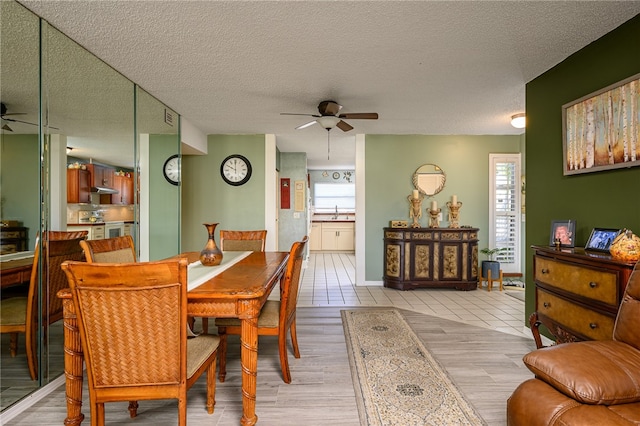 dining room featuring light hardwood / wood-style floors, ceiling fan, and a textured ceiling