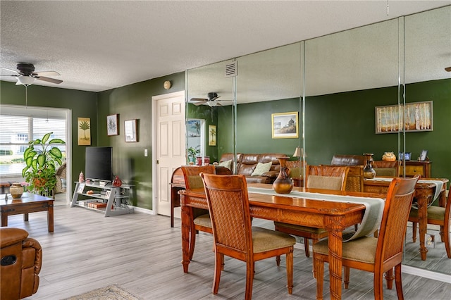 dining room featuring light wood-type flooring, a textured ceiling, and ceiling fan