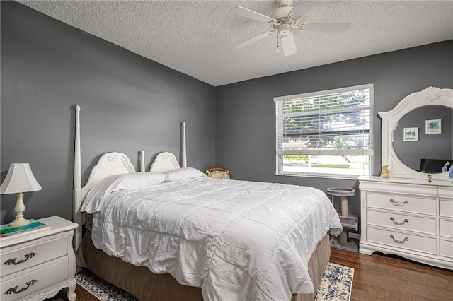 bedroom with a textured ceiling, ceiling fan, and dark hardwood / wood-style floors