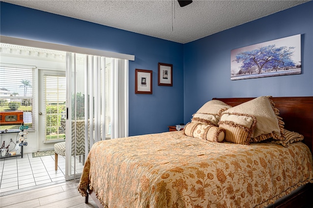 bedroom featuring light wood-type flooring, multiple windows, a textured ceiling, and ceiling fan