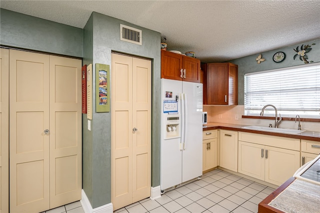 kitchen with tile countertops, sink, a textured ceiling, light tile patterned floors, and white fridge with ice dispenser