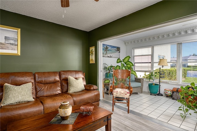 living room featuring ceiling fan, a textured ceiling, and light hardwood / wood-style floors