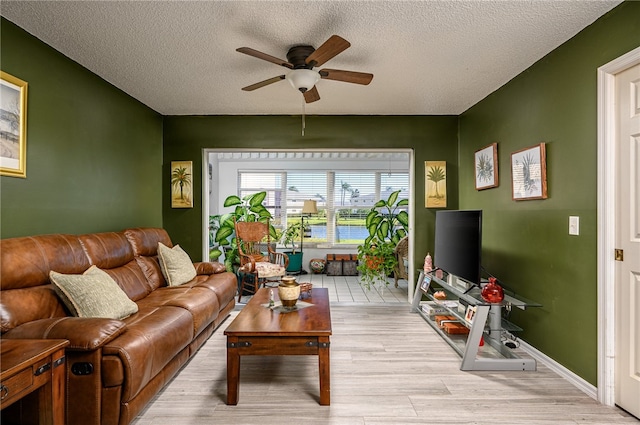 living room featuring light hardwood / wood-style floors, ceiling fan, and a textured ceiling