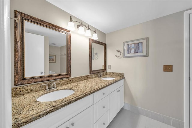 bathroom with double vanity, baseboards, tile patterned flooring, and a sink