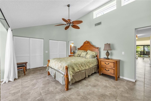 bedroom with a textured ceiling, visible vents, baseboards, two closets, and high vaulted ceiling