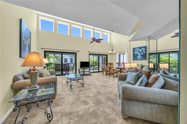 living area featuring a high ceiling and ceiling fan with notable chandelier