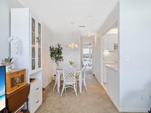 dining space with light carpet, an inviting chandelier, visible vents, and baseboards