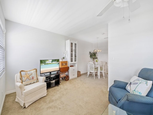 sitting room with carpet floors, baseboards, and ceiling fan with notable chandelier