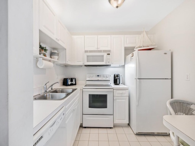 kitchen with light tile patterned floors, light countertops, white cabinetry, a sink, and white appliances