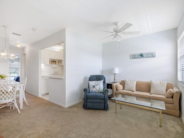 living room featuring visible vents, light carpet, baseboards, and ceiling fan with notable chandelier