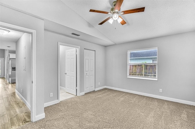 1545 22nd Ave SW, Vero Beach, FL 32962 - unfurnished bedroom featuring a textured ceiling, stainless steel fridge, lofted ceiling, light carpet, and a closet