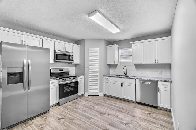 1545 22nd Ave SW, Vero Beach, FL 32962 - kitchen with appliances with stainless steel finishes, backsplash, white cabinetry, a textured ceiling, and light stone counters