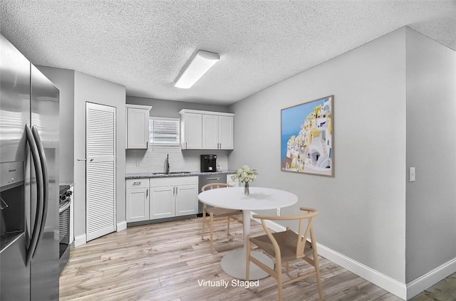 1545 22nd Ave SW, Vero Beach, FL 32962 - kitchen with appliances with stainless steel finishes, light wood finished floors, a textured ceiling, white cabinetry, and tasteful backsplash