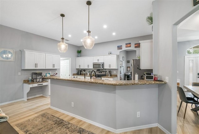 kitchen with kitchen peninsula, stone counters, pendant lighting, stainless steel appliances, and white cabinets
