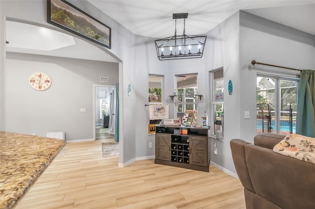 bar featuring pendant lighting, an inviting chandelier, and light hardwood / wood-style flooring