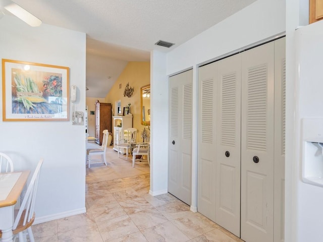 corridor with lofted ceiling and a textured ceiling