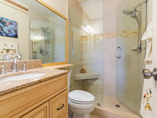 bathroom with vanity, toilet, and a shower with door