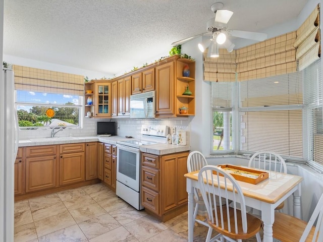 kitchen with decorative backsplash, a textured ceiling, white appliances, ceiling fan, and sink