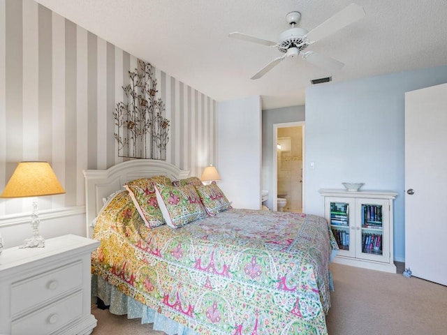 bedroom with ceiling fan, light colored carpet, and connected bathroom