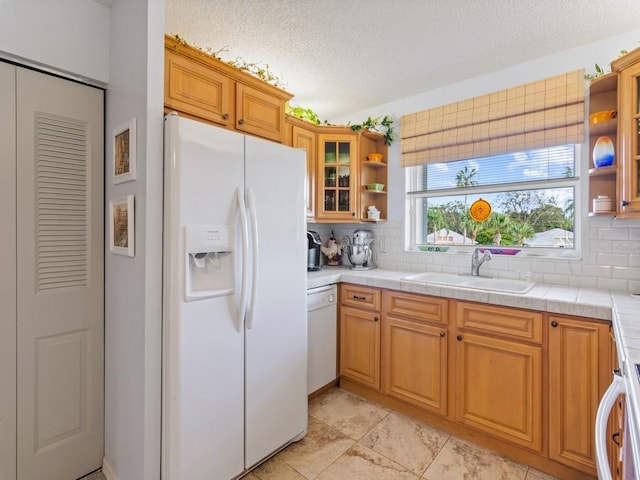 kitchen with a textured ceiling, decorative backsplash, sink, and white appliances