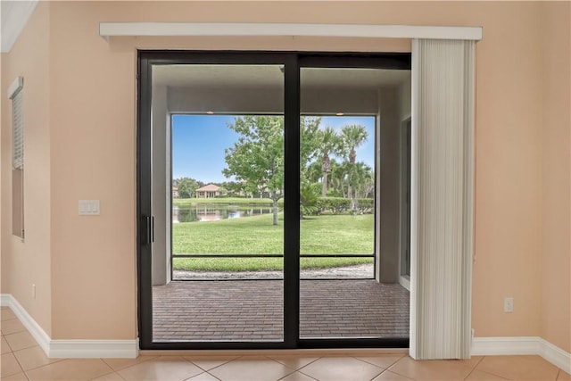 doorway to outside with a water view, light tile patterned floors, and plenty of natural light