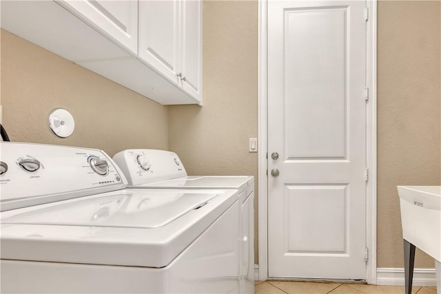 laundry area with light tile patterned flooring, cabinets, and washing machine and clothes dryer