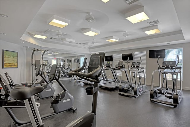 workout area with ceiling fan and a tray ceiling