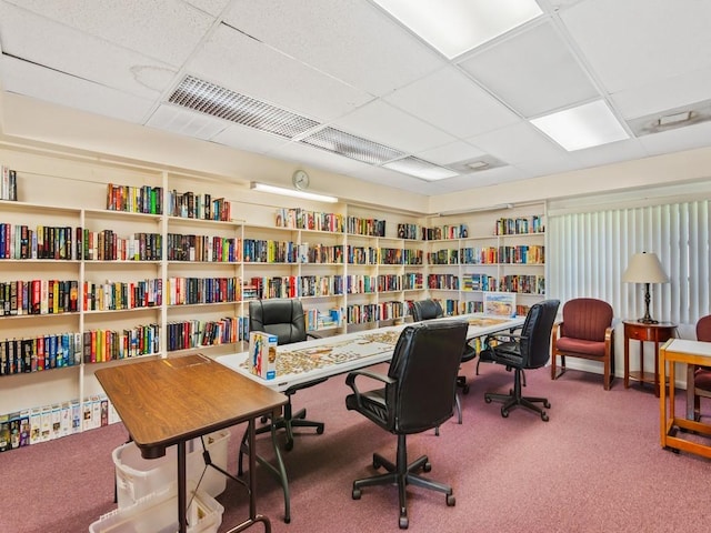 home office featuring carpet floors, a drop ceiling, wall of books, and visible vents
