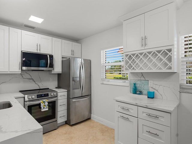 kitchen with light stone counters, decorative backsplash, appliances with stainless steel finishes, and white cabinets