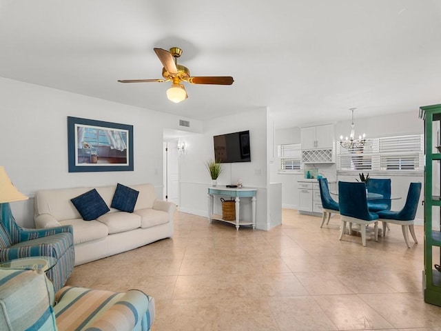 living area featuring light tile patterned floors, baseboards, ceiling fan with notable chandelier, and visible vents