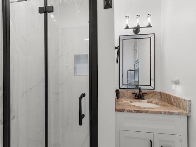 full bathroom with a marble finish shower and vanity