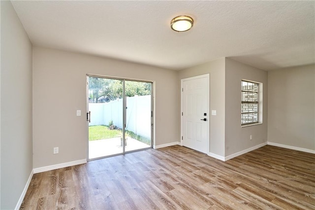 interior space with a textured ceiling, baseboards, and wood finished floors