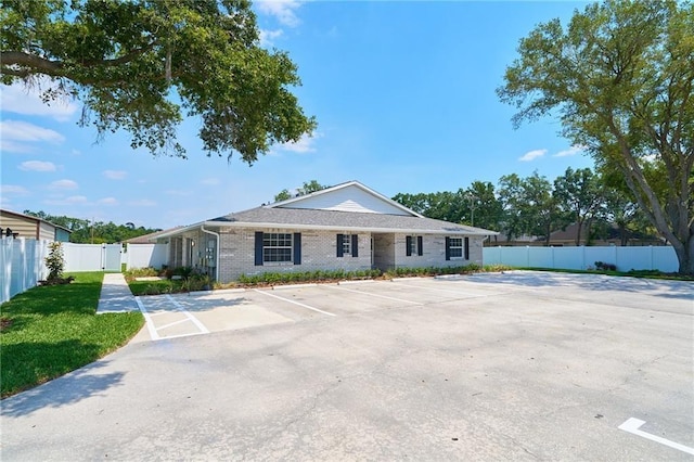 single story home featuring brick siding, uncovered parking, a gate, and fence