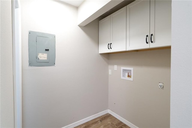 laundry room featuring baseboards, washer hookup, electric panel, wood finished floors, and cabinet space