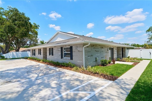 single story home with a front lawn, a gate, fence, and brick siding