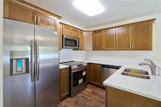 kitchen featuring a sink, stainless steel appliances, dark wood-type flooring, and brown cabinetry