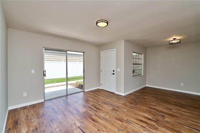 spare room featuring wood finished floors, baseboards, and a textured ceiling