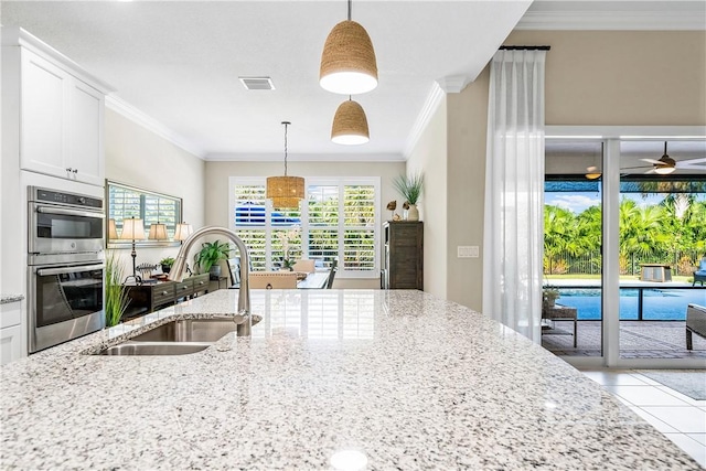 kitchen with pendant lighting, double oven, crown molding, and sink