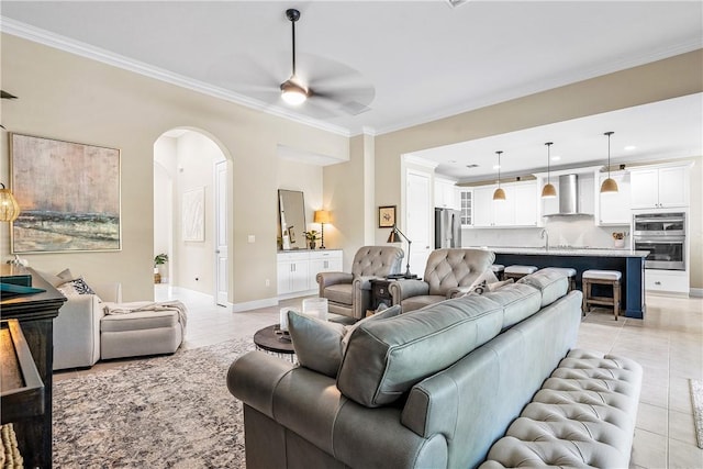 living room with ceiling fan, crown molding, light tile patterned floors, and sink